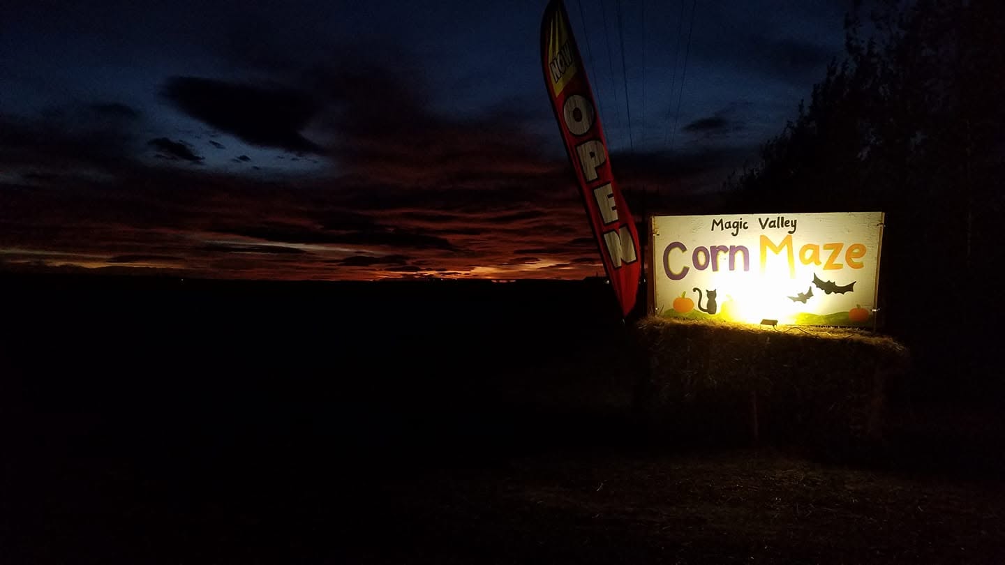 Magic Valley Corn Maze sign glowing against a sunset