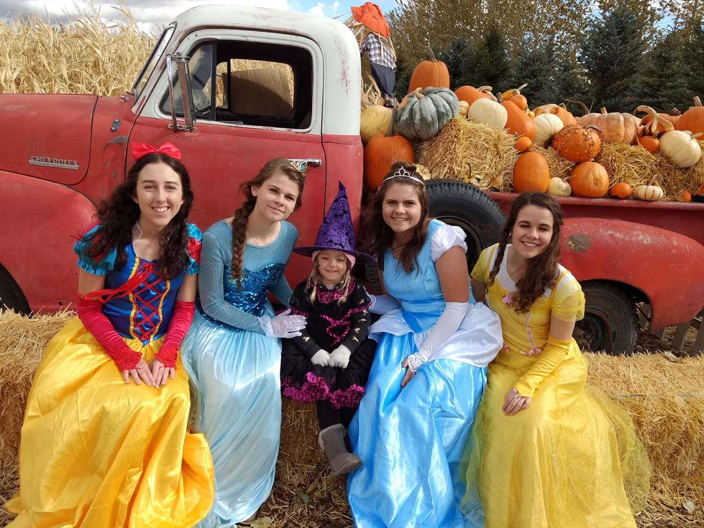 Costumed princesses posing beside the pumpkin truck