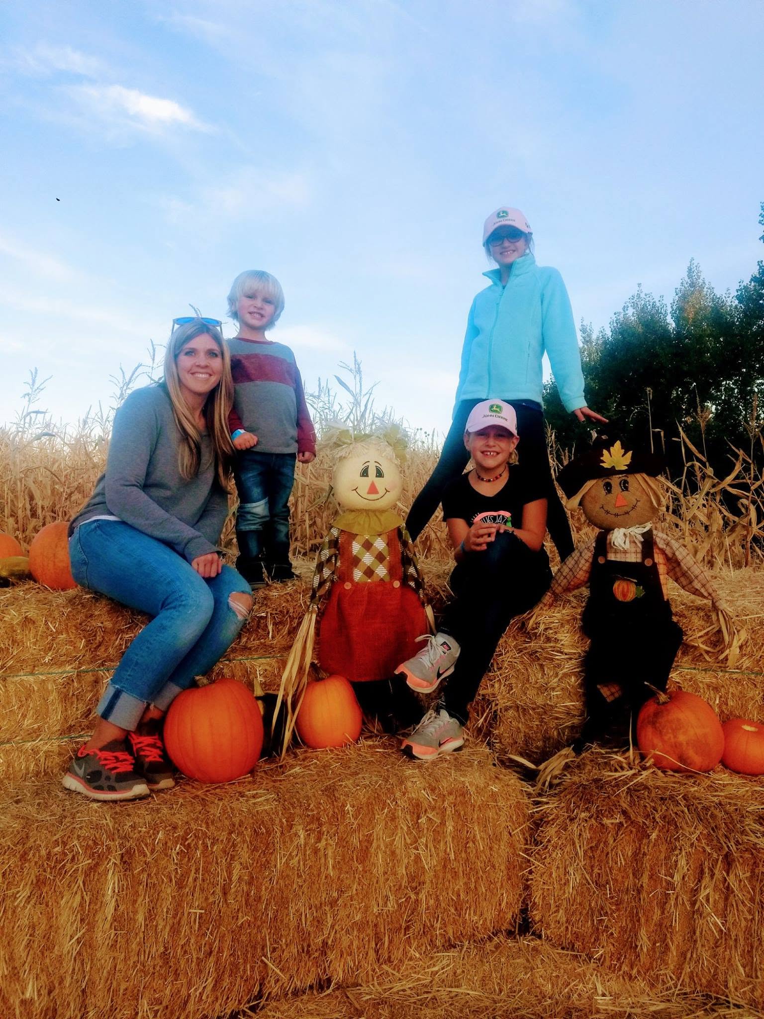 A family posing with pumpkins and scarecrows